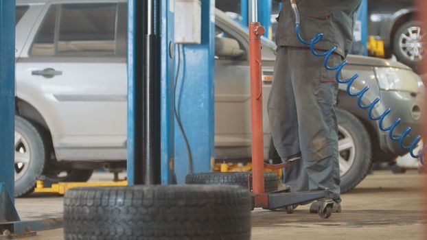 Car auto service working - mechanic under the car, close up