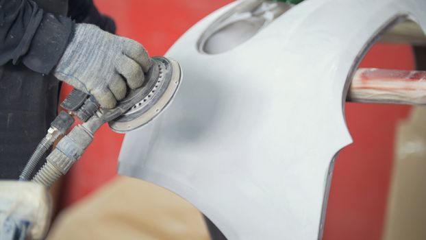 Man polishing bumper in a service station garage, slow motion