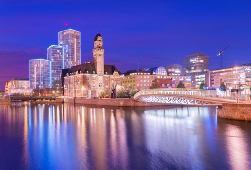 A view of a city at night. An evening panorama of Malmo is reflected on the water, Sweden. Long exposure photo with smooth nice reflections