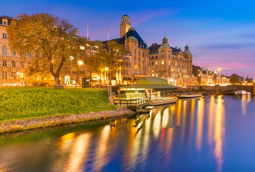Beautiful sunset in Malmo, Sweden. Picturesque evening cityscape. Old historical buildings, canal with boats at the wharf, colorful reflections in the water