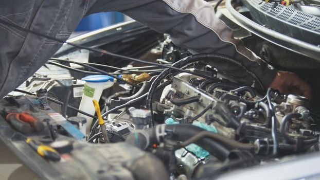 Man working with wiring on the dashboard at service station, close up