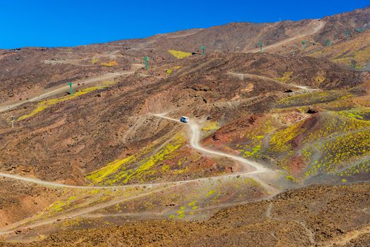 Scenic view of a mountain road with a bus moving to the top. Volcanic stone hills on The Mount Etna. Sicily, Italy