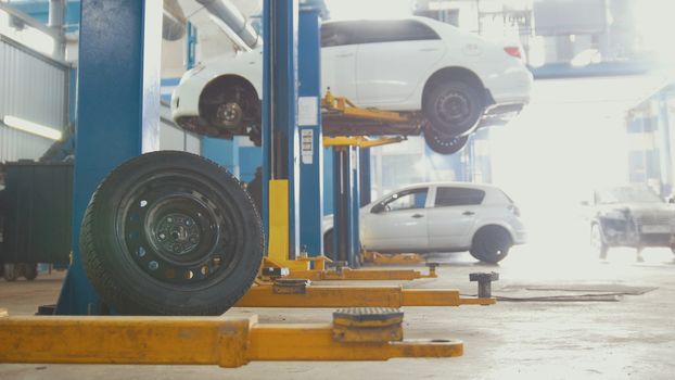 The tire in front of a service station with cars on the lift, blurred