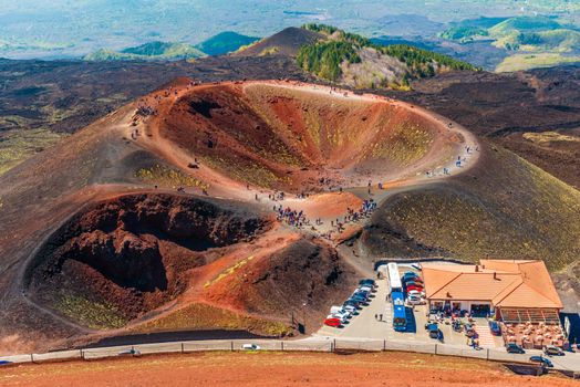 Stunning view at the volcanic crater and groups of tourists walking around it. Mount Etna, Sicily, Italy