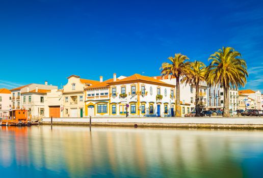 Cityscape of Aveiro, ("The Portuguese Venice"), Portugal. View of embankment with colorful buildings in the traditional architecture style, canal for boats and ships and several big palm trees