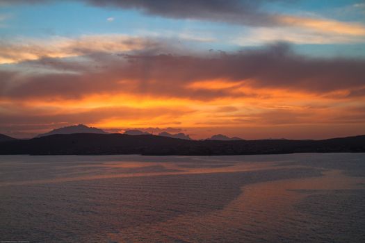 Sunrise on the Sardinian sea coast with intense orange color seen from the sea