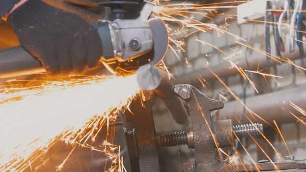 Blacksmith worker in forg making detail with circular saw, close up