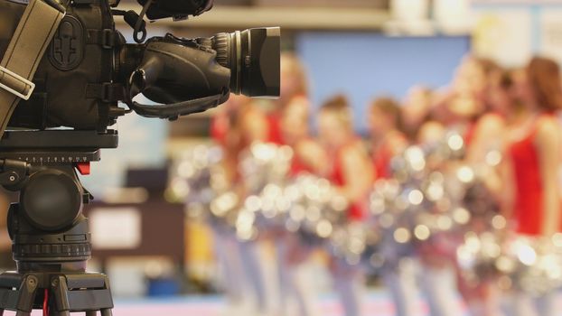 Camera in front of girls cheerleaders at sport championship, blurred