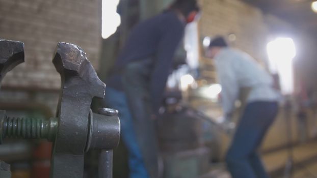 Blacksmith forging red hot iron on anvil - automatic hammering, de-focused shot