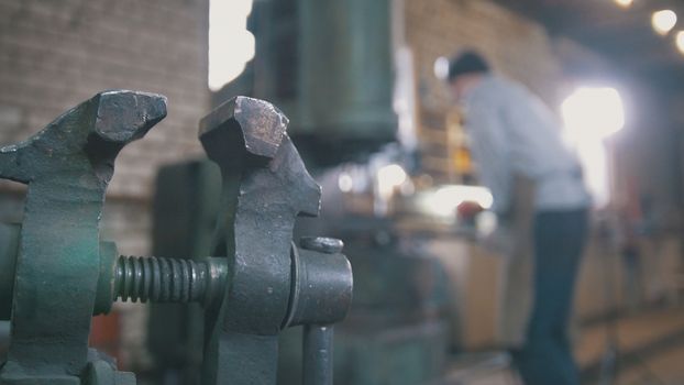 Blacksmith forging red hot iron on anvil - automatic hammering, de-focused shot