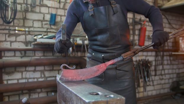 The blacksmith manually forging in the smithy, close up