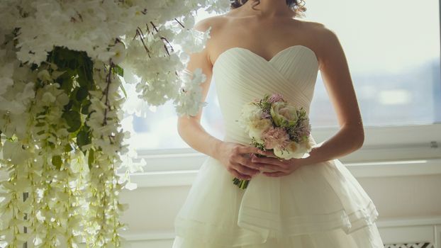 Attractive model in wedding dress with bride's bouquet, close up