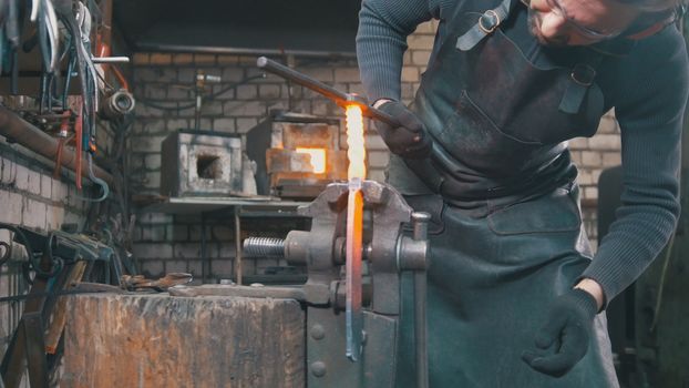 The farrier shaping the hot steel with a hammer in the forge, close up