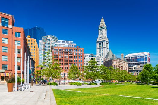 Boston - June 2016, MA, USA: View of The Custom House Tower, surrounding buildings in downtown and park with trees, lawn and benches