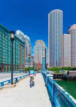 Boston, MA - June 2016, USA: Man cycling on bridge towards Boston downtown in sunny summer day