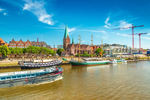 Bremen - July 2018, Germany: Cityscape of Bremen with old architecture, historical wooden sailing ships and barge floating along the river Weser