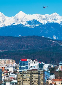 Ljubljana - March 2017, Slovenia: Ljubljana cityscape with snowy mountains on the background and police helicopter flying in the sky