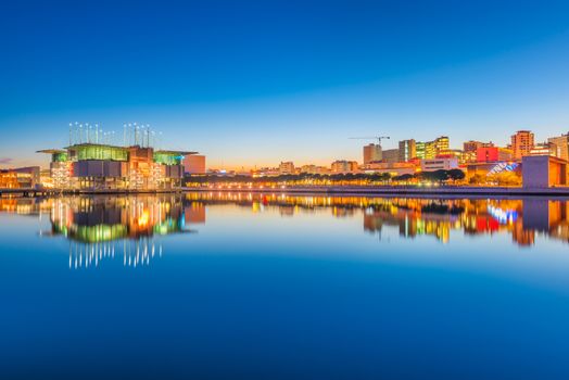 Lisbon - February 2019, Portugal: Evening cityscape mirrored in the water. View of The Park of Nations (Parque das Nações) and Oceanarium of Lisbon (Oceanário de Lisboa)