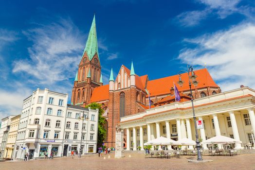 Schwerin - July 2018, Germany: View of the central square in Schwerin and one of its main landmarks - Cathedral (Schweriner Dom). People are walking around in the historic city center