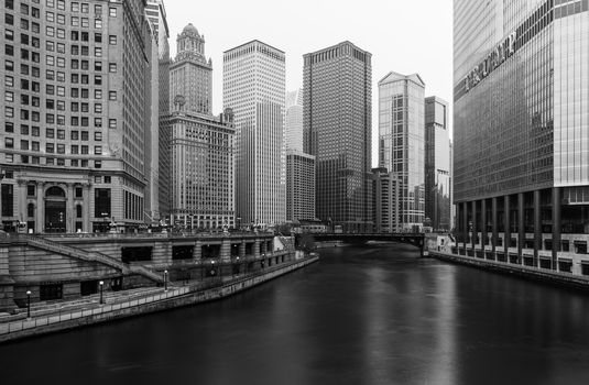 Chicago - March 2017, IL, USA: Black and white photo of Chicago downtown with skyscrapers, hotels, promenade and river viewed from the bridge, long exposure photography