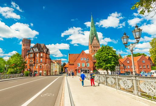 Luneburg - July 2018, Germany: Two women are walking on the bridge across the river. Cityscape of an old European city with traditional architecture