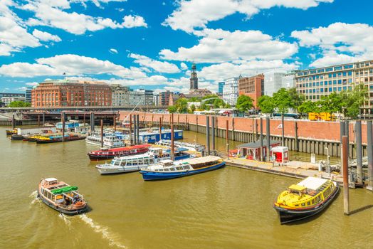 Hamburg - July 2018, Germany: Cityscape of Hamburg. Pier and colored boats. Touristic boat with people is floating along the canal