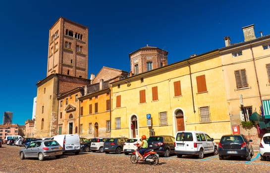 Mantua (Mantova) - July 2017, Lombardy (Lombardia) region, Italy: View of the street with traffic, old historical buildings and Mantua Cathedral with bell tower