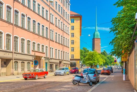Helsinki - June 2019, Finland: A street with a car traffic, Mikael Agricola Church and colorful residential buildings