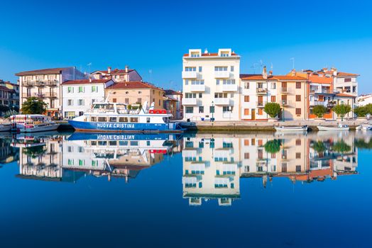 Grado - December 2015, Italy: Colored residential houses mirror reflected in canal with water.