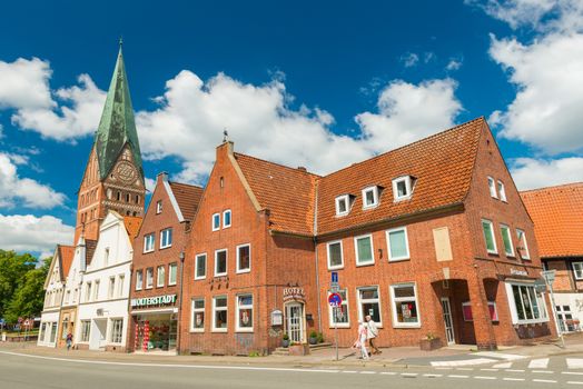 Luneburg - July 2018, Germany: Old houses built of red brick. Typical German architecture. St. John's Church on the background. People are walking along the street