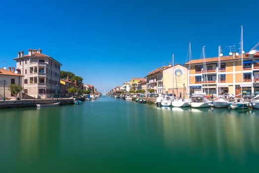 Grado - March 2016, Italy: Canal with sail boats lying on water in small Italian town of Grado