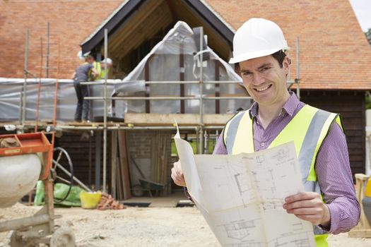 Architect On Building Site Looking At House Plans
