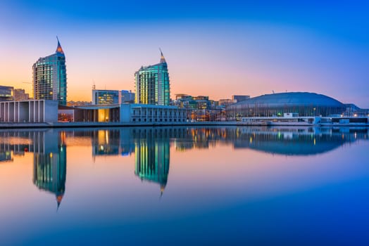 Lisbon - February 2019, Portugal: Sunset at The Nations Park (Parque das Nações) in Lisbon. Modern buildings and Altice Arena mirrored in the water