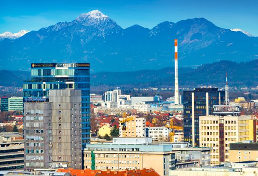 Ljubljana - December 2019, Slovenia: View of the modern buildings in downtown Ljubljana with beautiful snowy Alps in the background