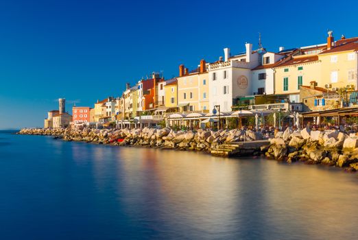 Piran - November 2014, Slovenia: View of the old city center reflected in the water of the Adriatic Sea, town of Piran during the sunset, coastline against the clear blue sky