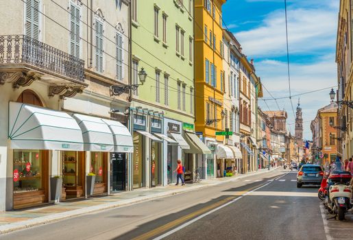 Parma - July 2017, Emilia Romagna, Italy: A street of Parma  with historical buildings, shops, pharmacy, parked car and scooter
