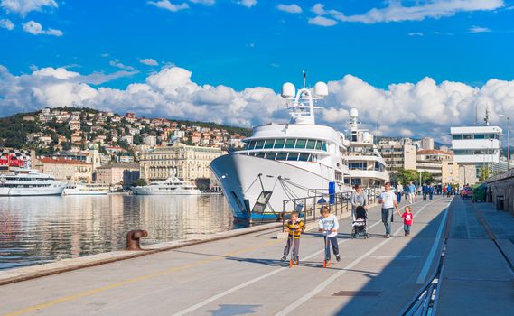 Rijeka - June of 2012, Croatia: View of Rijeka port, kids ride scooters on the pier