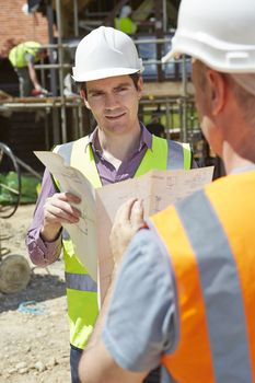 Architect Discussing Plans With Builder On Construction Site