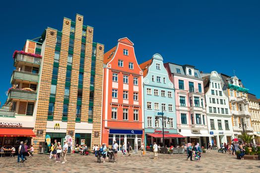 Rostock - July 2018, Germany: Colored historical houses on the central square of the city. People are walking along the street