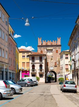 Rovigo - July 2017, Veneto region, Italy: View of the old tower with arch, surrounding buildings and parked cars