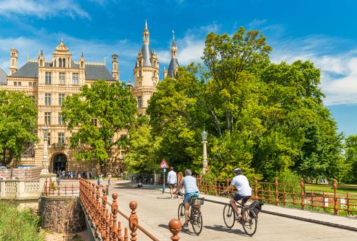 Schwerin - July 2018, Germany: Two cyclists moving towards the Schwerin Castle, the most famous landmark of the state of Mecklenburg-Vorpommern