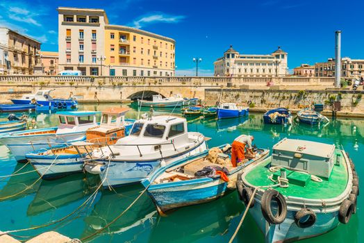 Syracuse - April 2019, Sicily, Italy: Cityscape of Syracuse with colorful boats, bridge and historical buildings with blue sky in the background