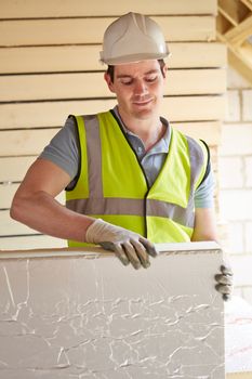 Builder Fitting Insulation Boards Into Roof Of New Home