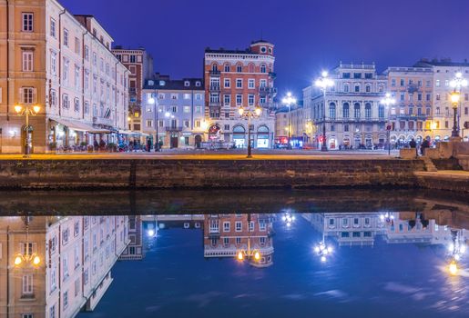 Trieste - December 2016, Italy: Night view of Trieste, old buildings mirror reflected in water, Grand Canal in Trieste city center