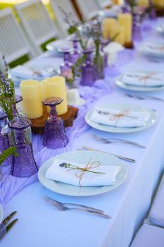 Elegant table setting for wedding engagement Easter dinner with white ceramic plates cotton napkin tied with twine lavender flowers candles. Provence style.