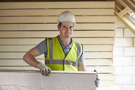 Builder Fitting Insulation Boards To Roof Of New House