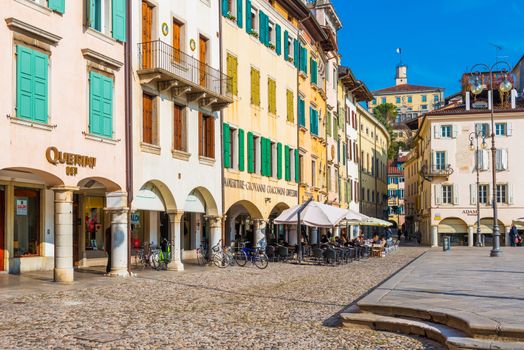 Udine - February 2017, Friuli Venezia Giulia, Italy: The street of Udine with traditional architecture and the stone pavement. Central square of the city. People sitting in cafe