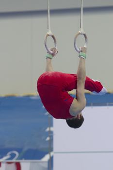 Athletic man performing with gymnastic rings at the competition, close up