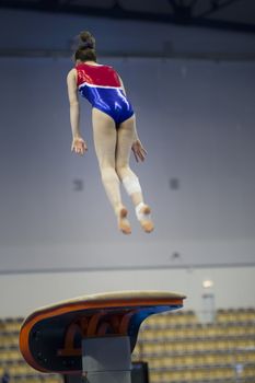 Female athlete gymnast performing a leap at the championship, telephoto shot