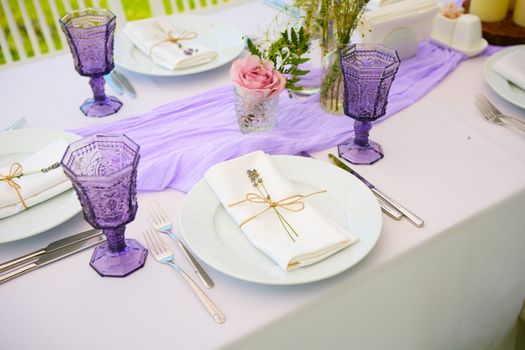 Elegant table setting for wedding engagement Easter dinner with white ceramic plates cotton napkin tied with twine lavender flowers candles. Provence style.